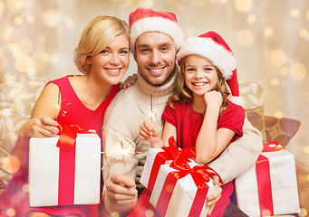 Image showing smiling family holding gift boxes and sparkles