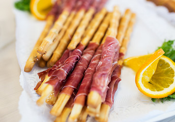 Image showing close up of grissini bread sticks with prosciutto