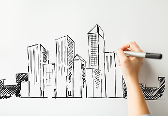 Image showing close up of hand drawing city on white board