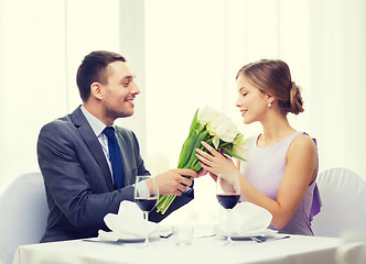 Image showing smiling man giving flower bouquet at restaurant