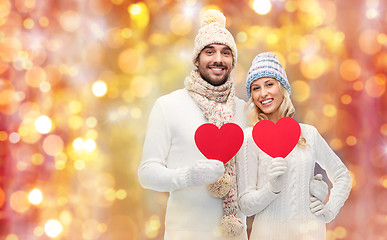 Image showing smiling couple in winter clothes with red hearts