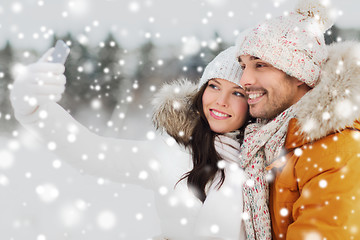 Image showing happy couple taking selfie by smartphone in winter