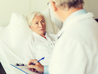 Image showing senior woman and doctor with clipboard at hospital