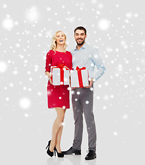 Image showing happy couple with christmas gift boxes over snow