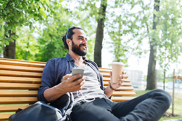 Image showing man with earphones and smartphone drinking coffee