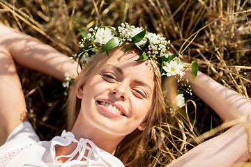 Image showing happy woman in wreath of flowers lying on straw