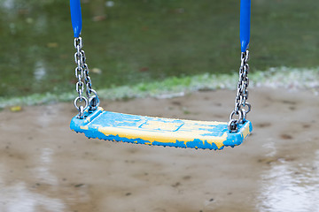 Image showing Plastic swing hanging over a puddle