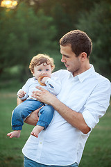 Image showing Young beautiful father and little toddler son against green grass