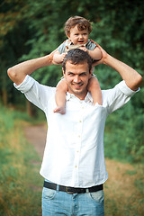 Image showing Young beautiful father and little toddler son against green trees