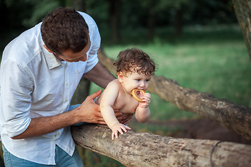 Image showing Young beautiful father and little toddler son against green grass