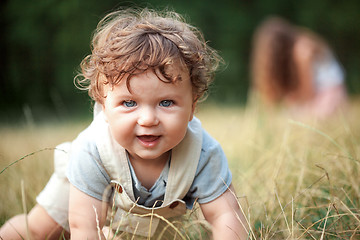 Image showing The little baby or year-old child on the grass in sunny summer day.