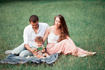 Image showing Young beautiful father, mother and little toddler son against green trees