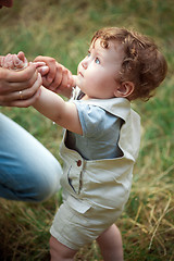 Image showing The little baby or year-old child on the grass in sunny summer day.