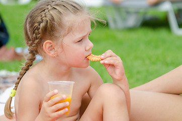 Image showing Girl eating cookies and drinking juice from a plastic disposable cup