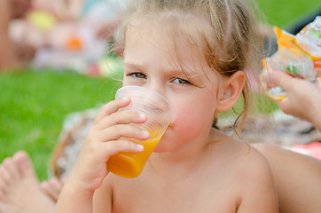 Image showing Girl drinking fruit juice from a plastic disposable cup and looked into the frame