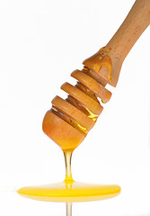 Image showing Honey dripping from a wooden honey dipper 