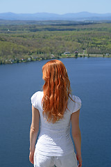 Image showing Red-haired girl looking over blue lake