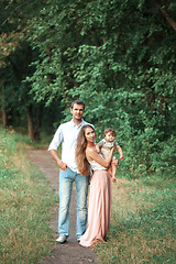 Image showing Young beautiful father, mother and little toddler son against green trees