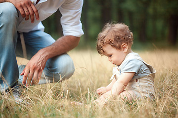 Image showing Young beautiful father and little toddler son against green grass