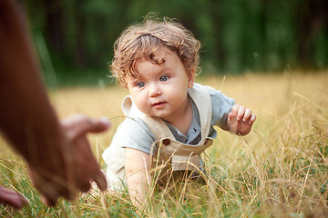 Image showing The little baby or year-old child on the grass in sunny summer day.