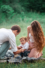 Image showing Young beautiful father, mother and little toddler son against green trees