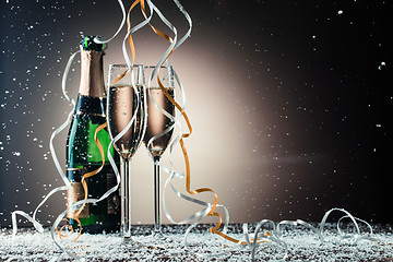 Image showing Glasses with sparkling champagne, green bottle and cascading ribbons