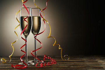 Image showing Two champagne glasses on table decorated yellow and red ribbons