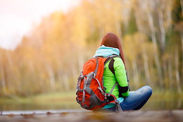 Image showing Brunette sitting back on bridge in autumn