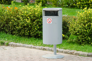 Image showing Accurate cylindrical metal rubbish bin on a background of a well-kept lawn