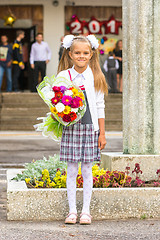 Image showing Grower Baby girl first-grader with a bouquet of flowers at the school