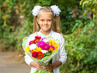 Image showing Up portrait of a seven-year school girl with a bouquet of flowers
