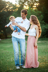 Image showing Young beautiful father, mother and little toddler son against green trees