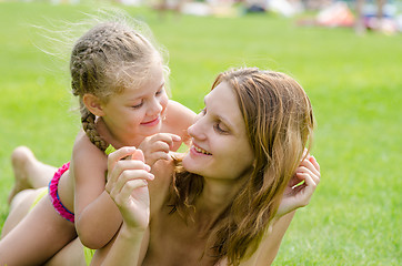 Image showing Mom and daughter having fun lying on a green lawn in the summer