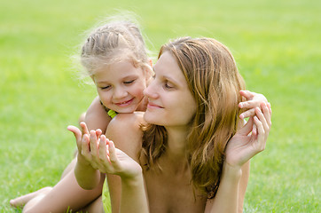 Image showing Mom and daughter having fun embrace the summer picnic on a green lawn