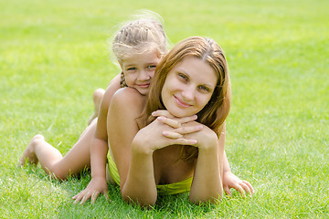 Image showing Mum and daughter lie on a green lawn in a bikini and look in the frame