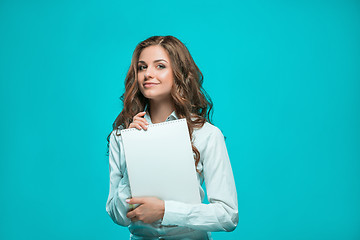 Image showing The smiling young business woman with pen and tablet for notes on blue background