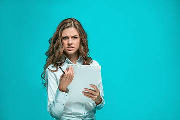 Image showing The thoughtful young business woman with pen and tablet for notes on blue background