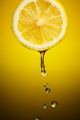 Image showing Lemon slice and drops of juice on orange background
