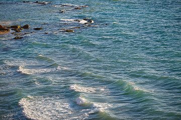 Image showing Turquoise sea and light waves lapping protruding stones