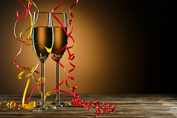 Image showing Two glasses of champagne decorated with gold and red streamer