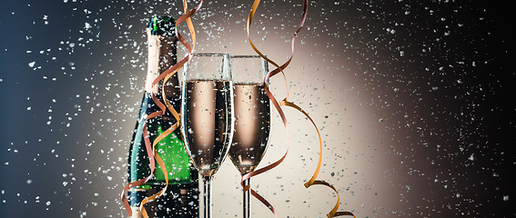 Image showing Two wineglasses with champagne closeup, bottle, ribbons and snowflakes