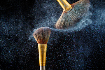 Image showing Thick professional brushes making blue powder cloud on black background