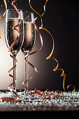 Image showing Champagne glasses with ribbons and snowflakes on dark background
