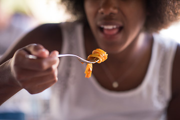 Image showing a young African American woman eating pasta