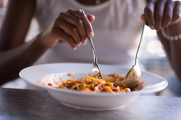 Image showing a young African American woman eating pasta