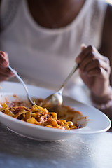 Image showing a young African American woman eating pasta