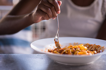 Image showing a young African American woman eating pasta