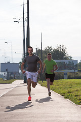 Image showing Two young men jogging through the city