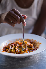 Image showing a young African American woman eating pasta