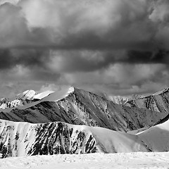 Image showing Black and white winter snow mountains in dark storm clouds